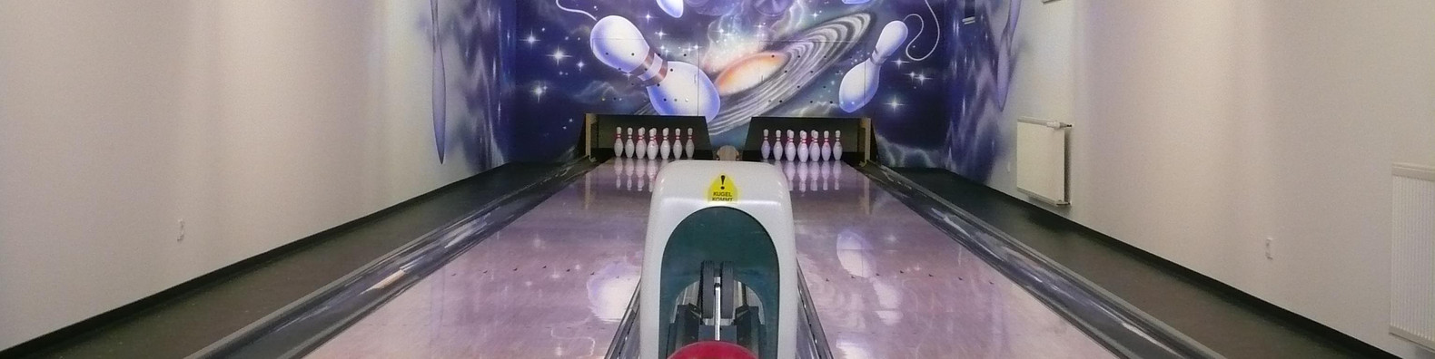 2 Bowlingbahnen mit Bowlingkugeln und 2 Monitore hängen von der Decke.