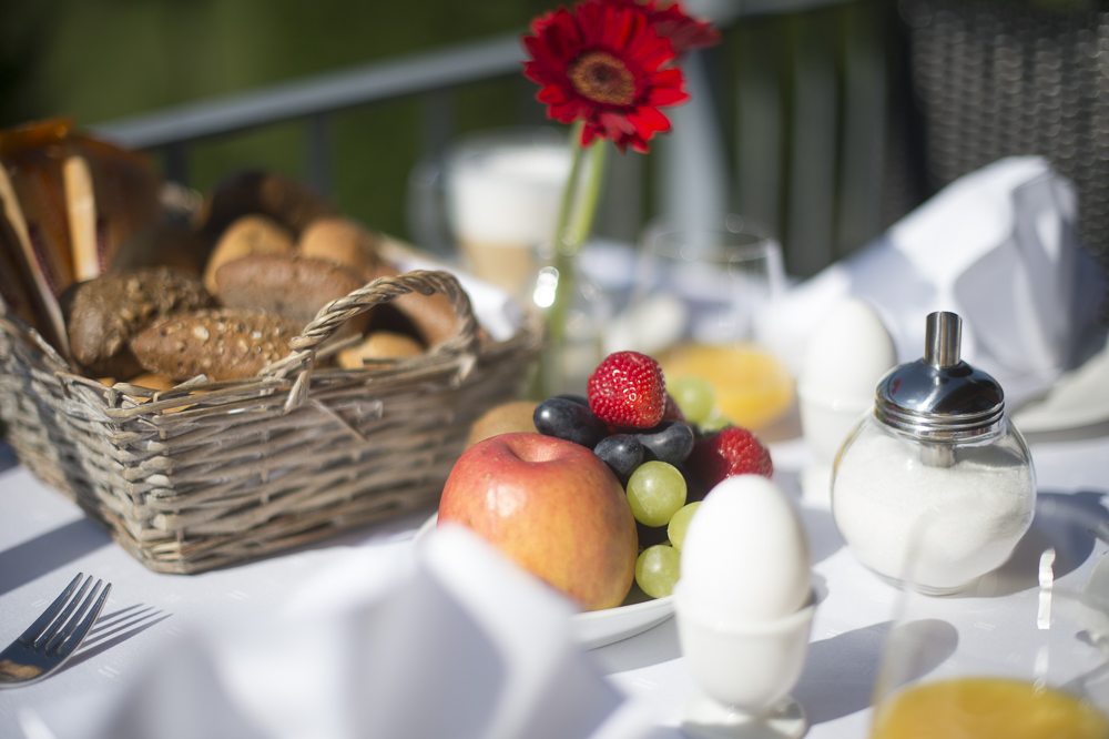 Frühstück auf Terrasse mit Brötchen, Obst und Ei