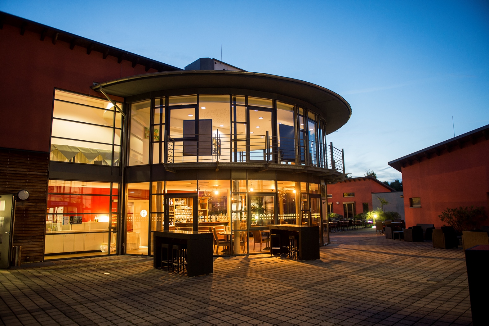Restaurant von außen, Hofperspektive, am Abend, von innen erleuchtet